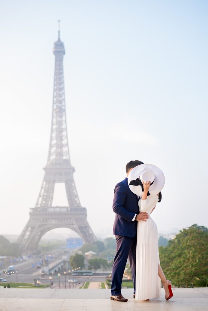 a man and woman kissing in front of the eiffel tower