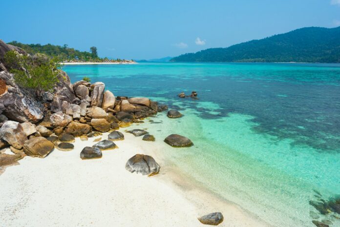 A beach with rocks and clear blue water