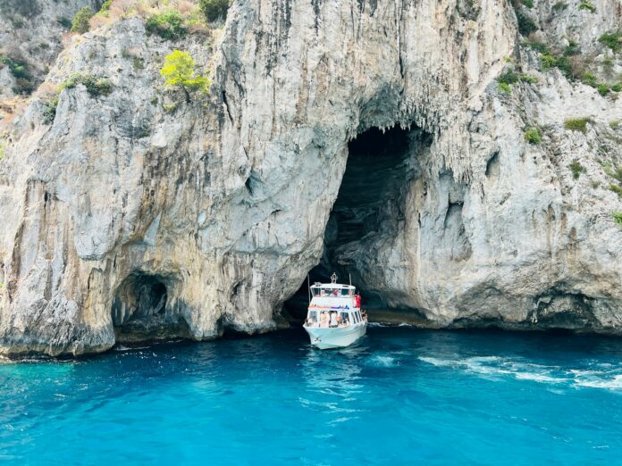 a boat in the water near a large rock formation