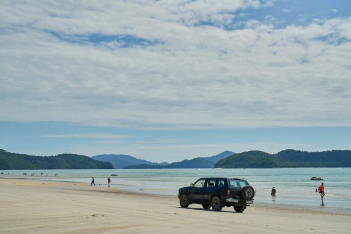 a truck is parked on the beach near the water