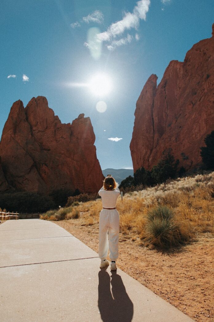 a person standing on a sidewalk in front of mountains