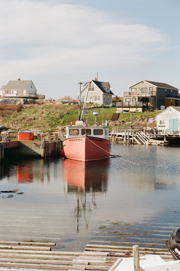 A red boat sitting in the water next to a dock