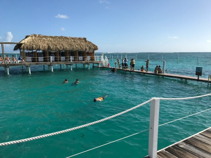 people swimming on sea near brown wooden beach house during daytime