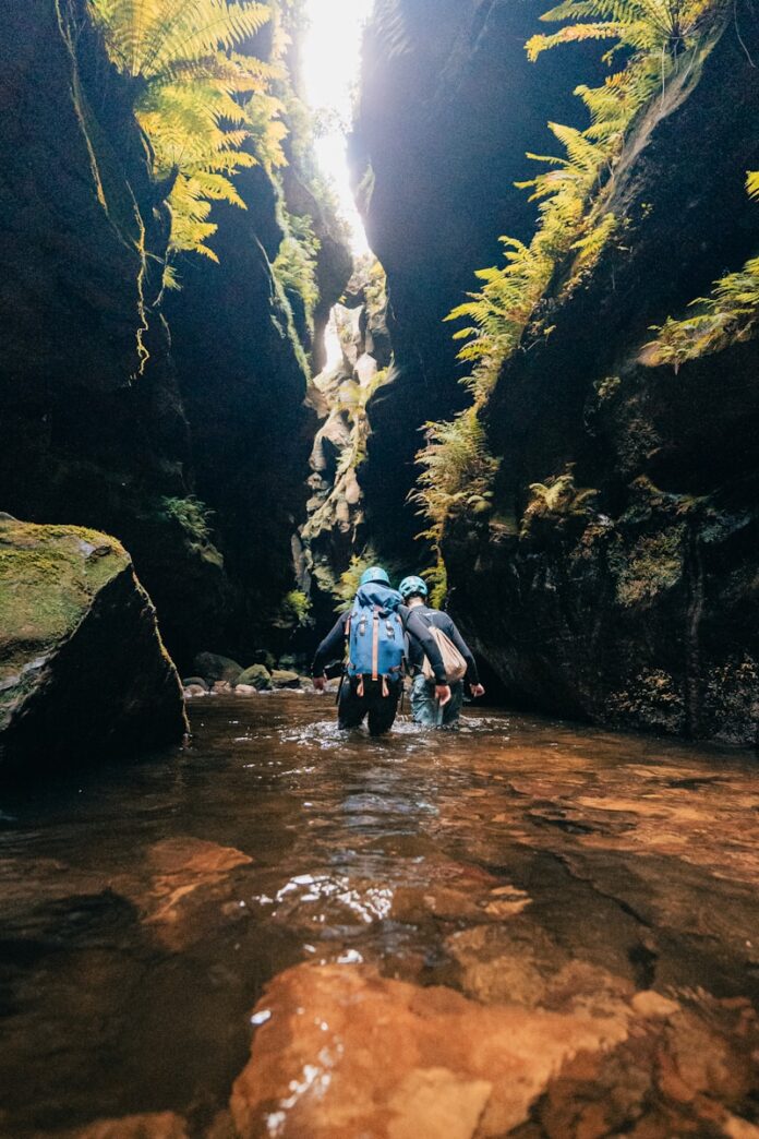 A person walking through a narrow river in a canyon