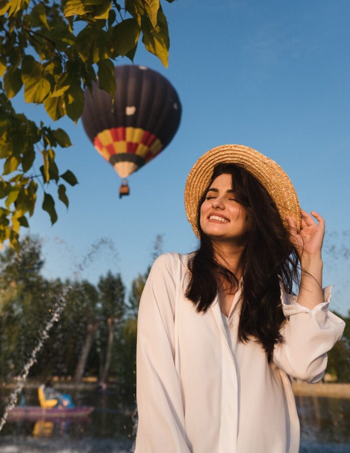 woman in white long sleeve shirt wearing brown woven hat