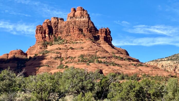 a large red rock formation surrounded by trees