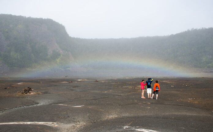 a group of people standing in a field under a rainbow